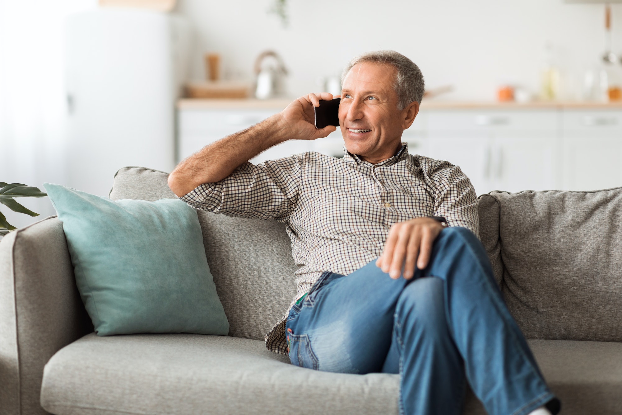 Happy Senior Man Talking On Mobile Phone Sitting At Home