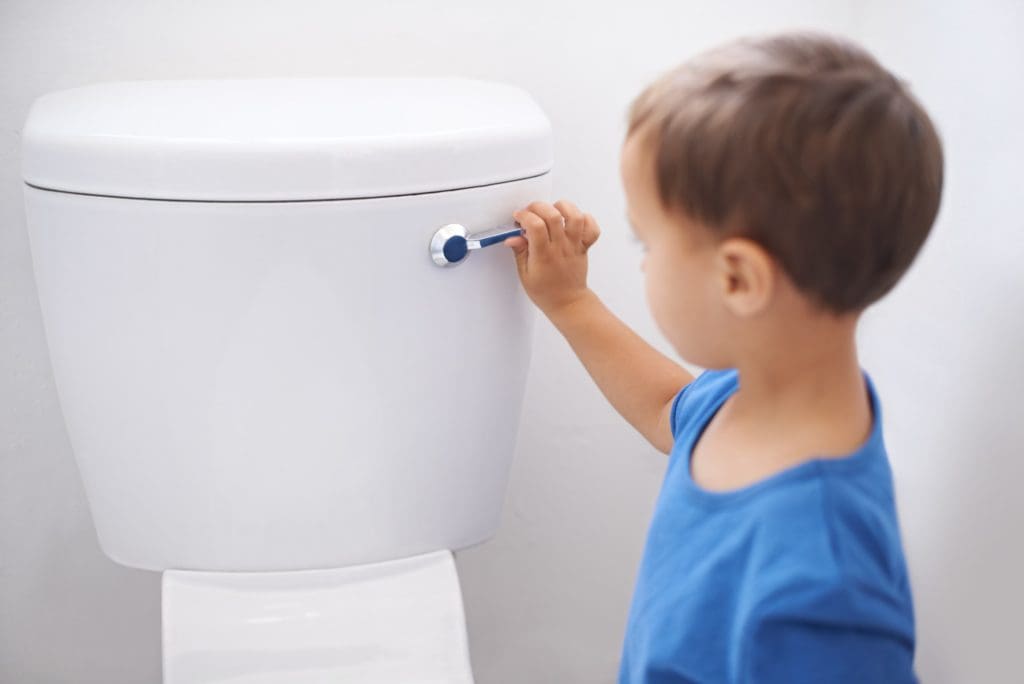 All done. Shot of a cute young boy flushing a toilet.