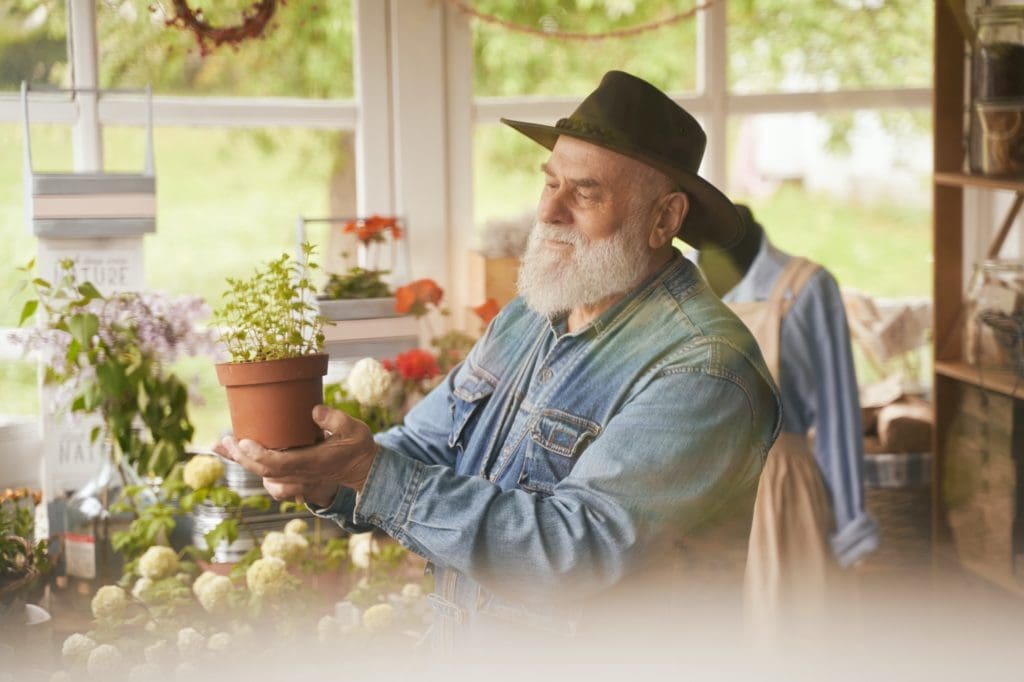 Happy old man enjoying work in own flower shop after having septic tank pumped